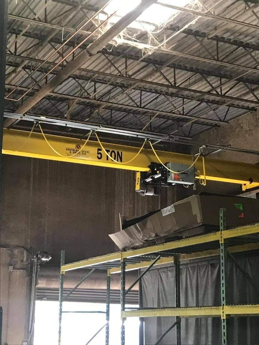 Yellow overhead crane in a warehouse, labeled 