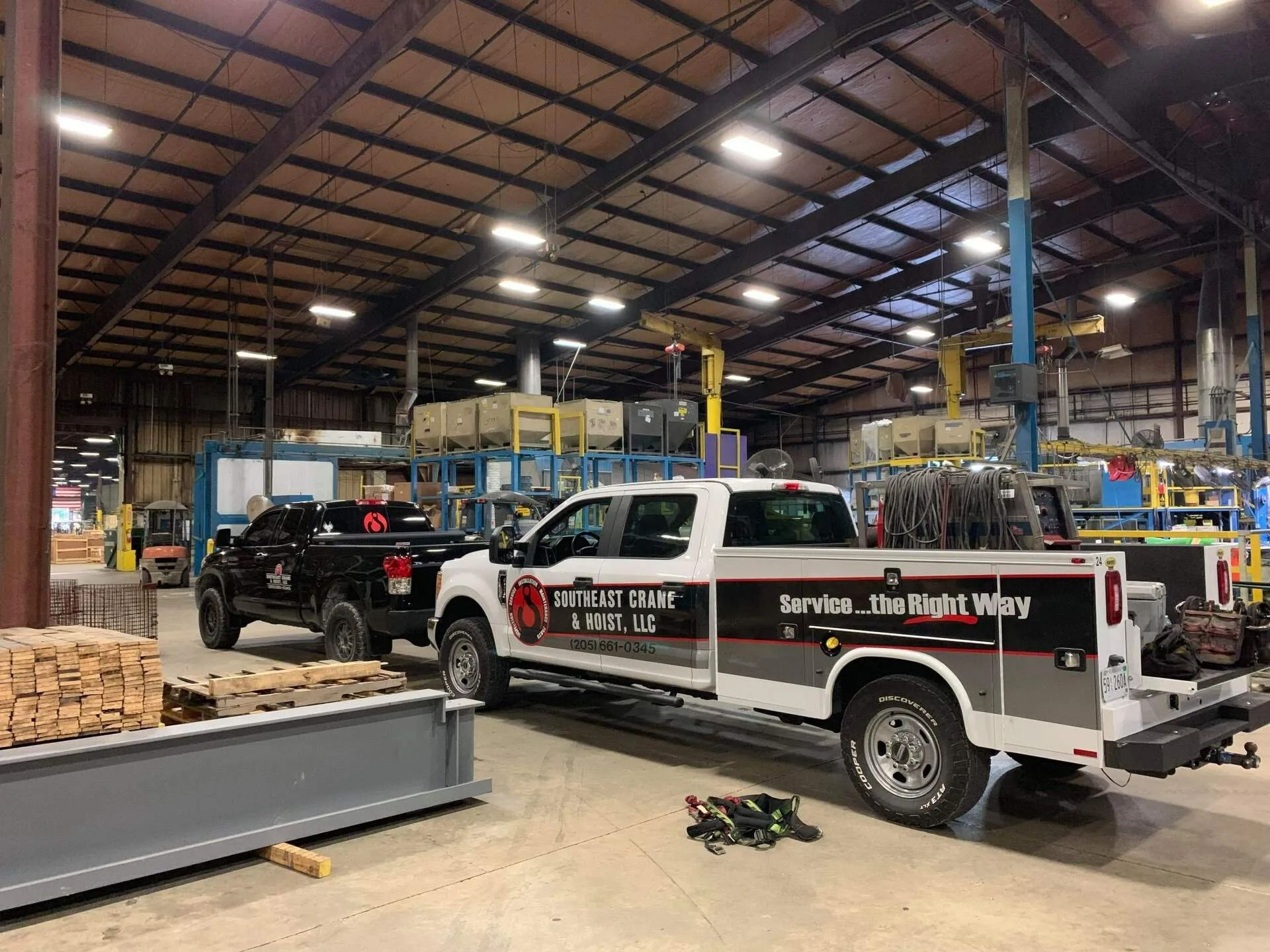 Two service trucks parked inside a large warehouse.