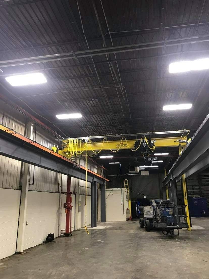 Warehouse interior with a yellow overhead crane and a utility cart.