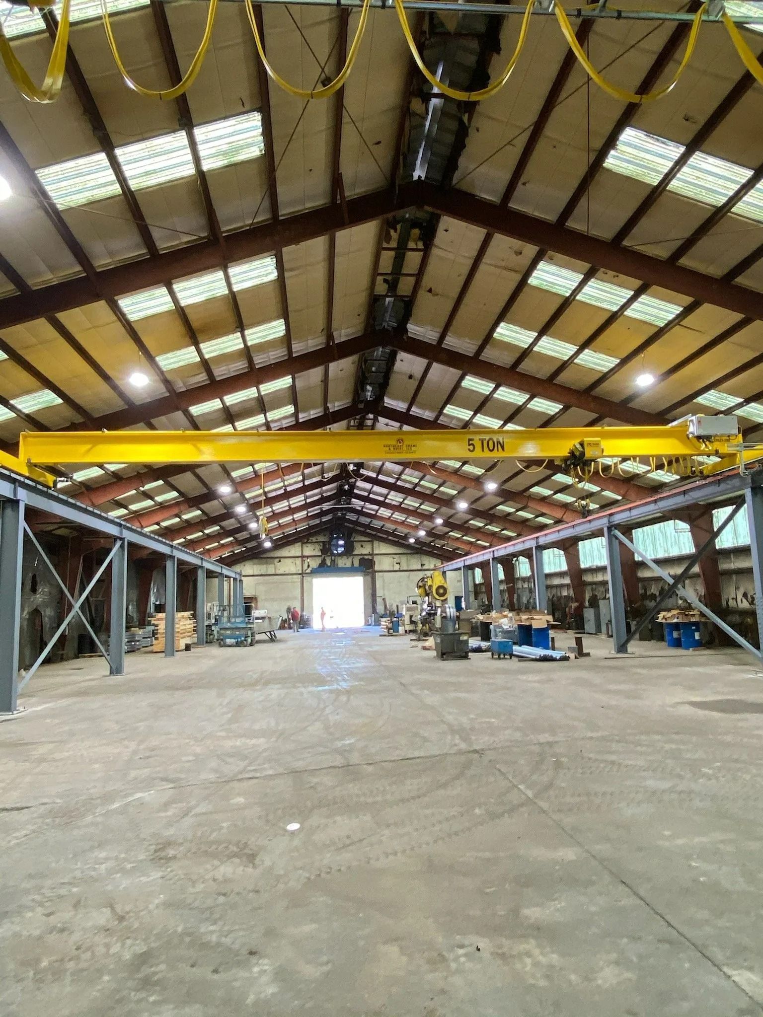 Large industrial warehouse interior with a yellow overhead crane.