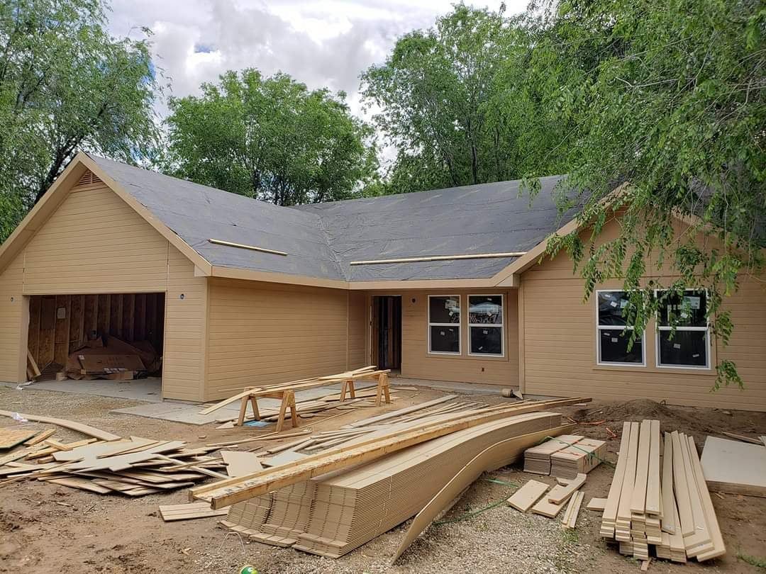 A house is being built with a lot of wood in front of it.