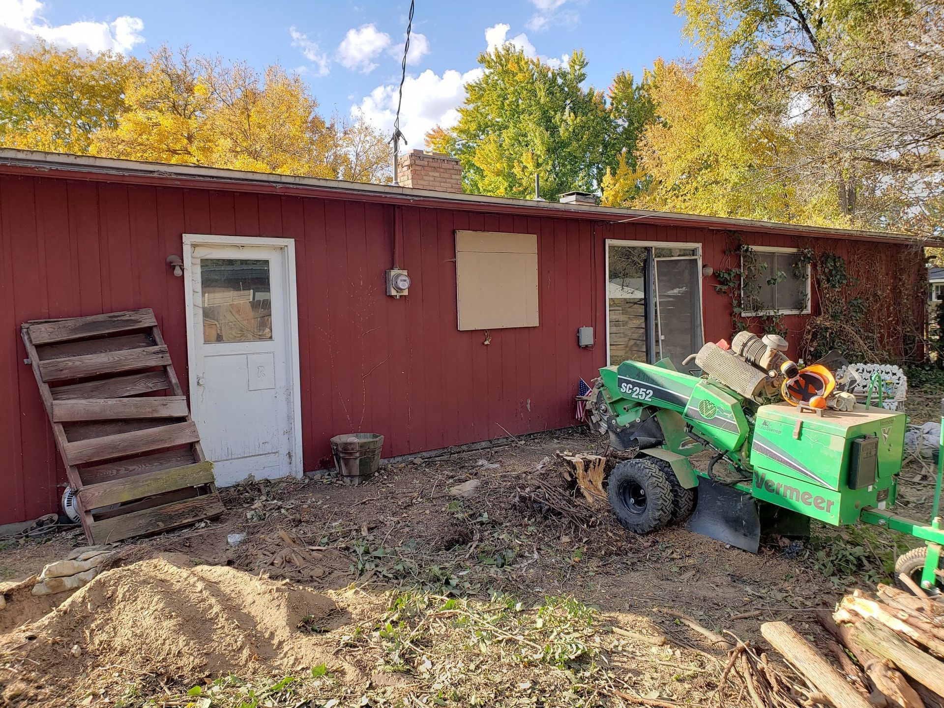 A green tractor is parked in front of a red building.