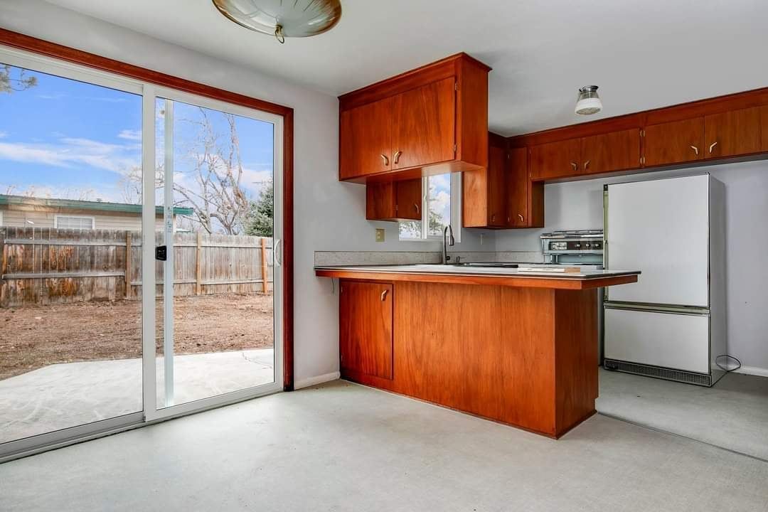 An empty kitchen with sliding glass doors and wooden cabinets