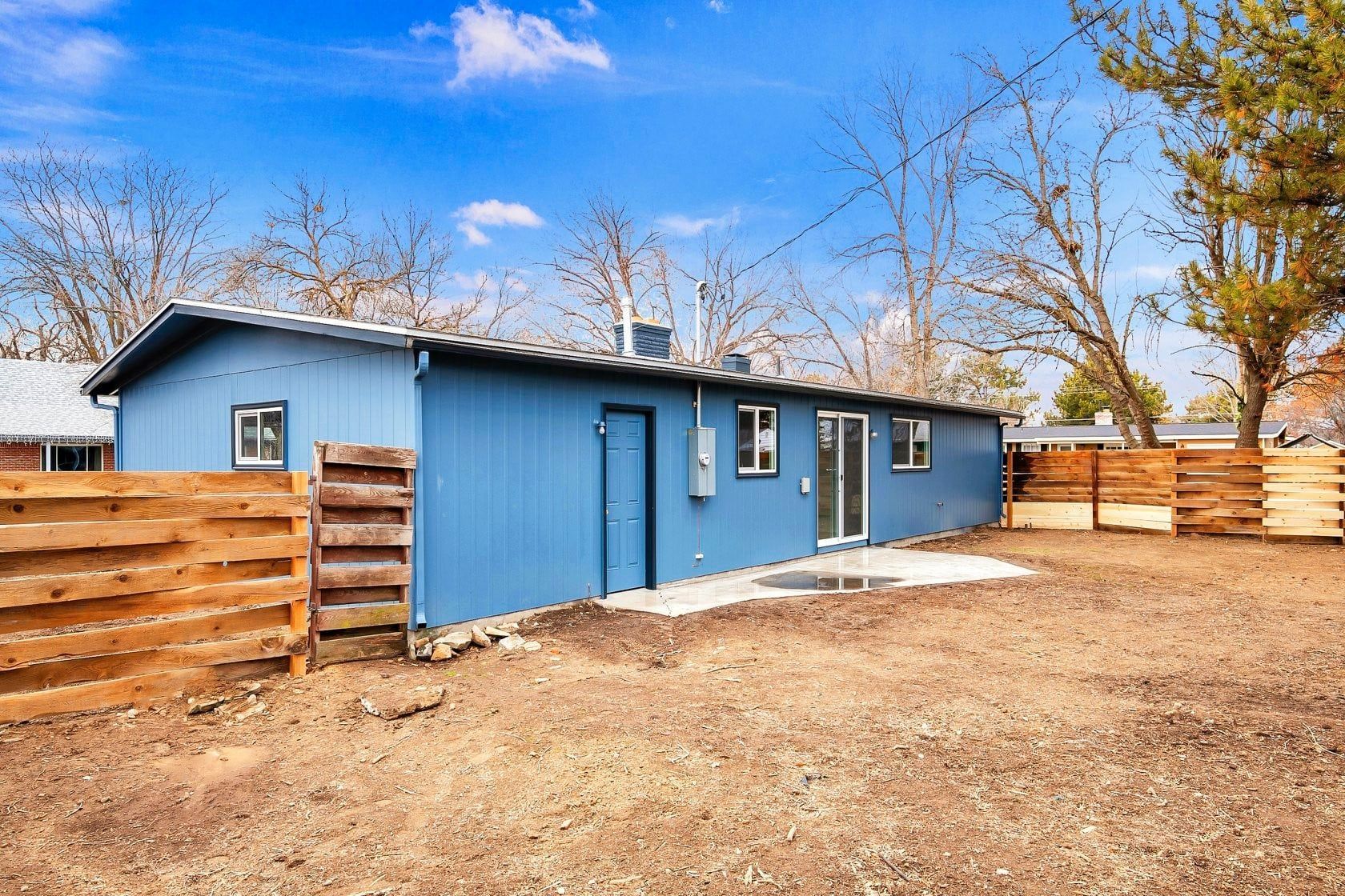 A blue house with a wooden fence in front of it.