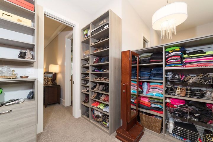 a walk in closet with lots of shoes and clothes