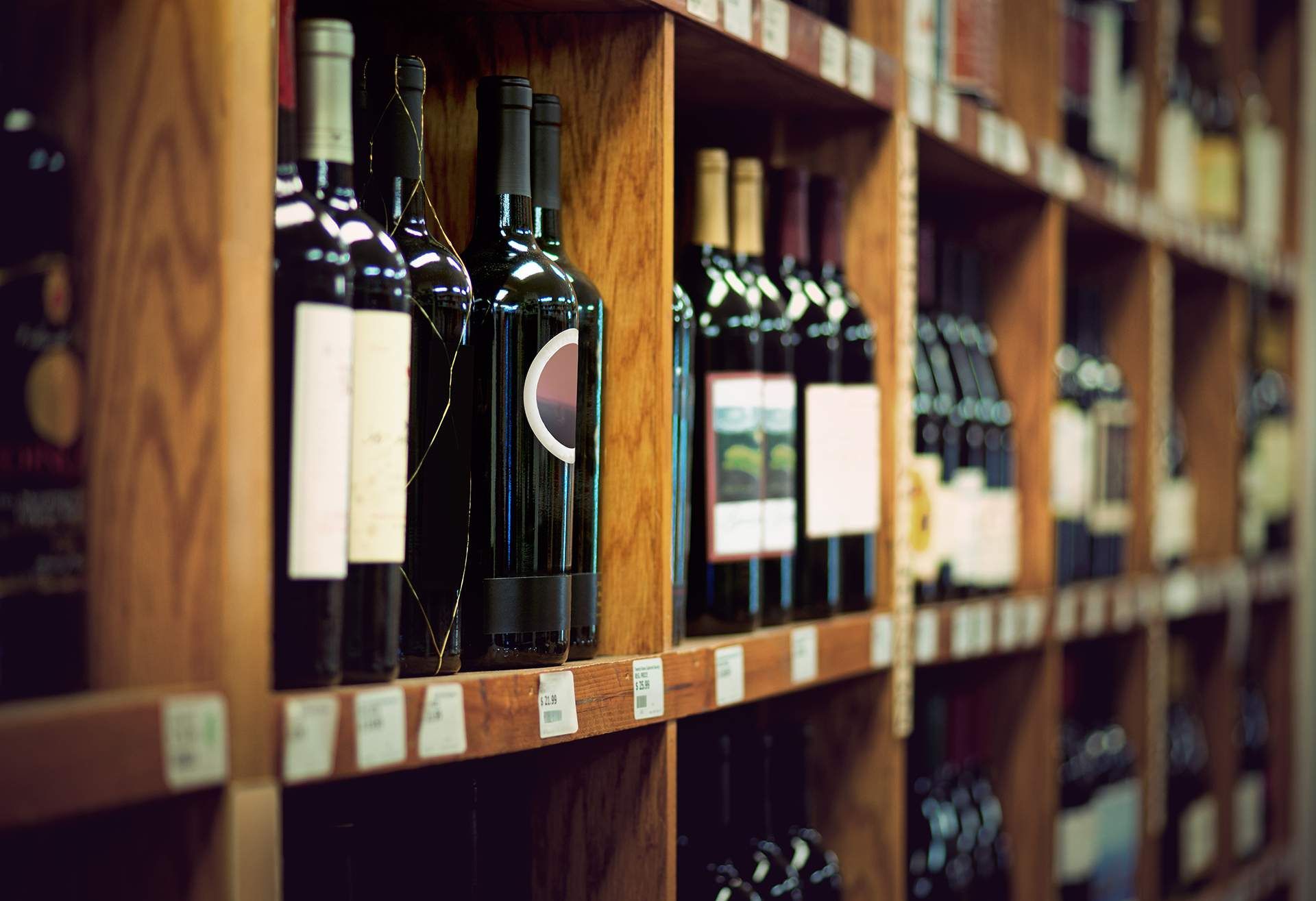 several bottles of wine are lined up on wooden shelves