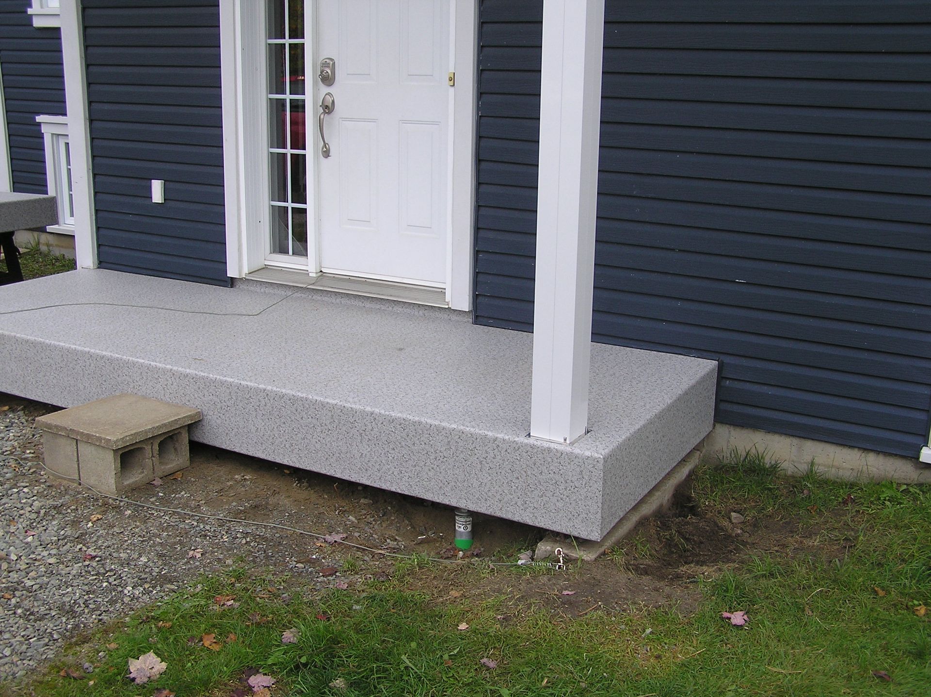 Une maison bleue avec un porche en PVC et une porte blanche