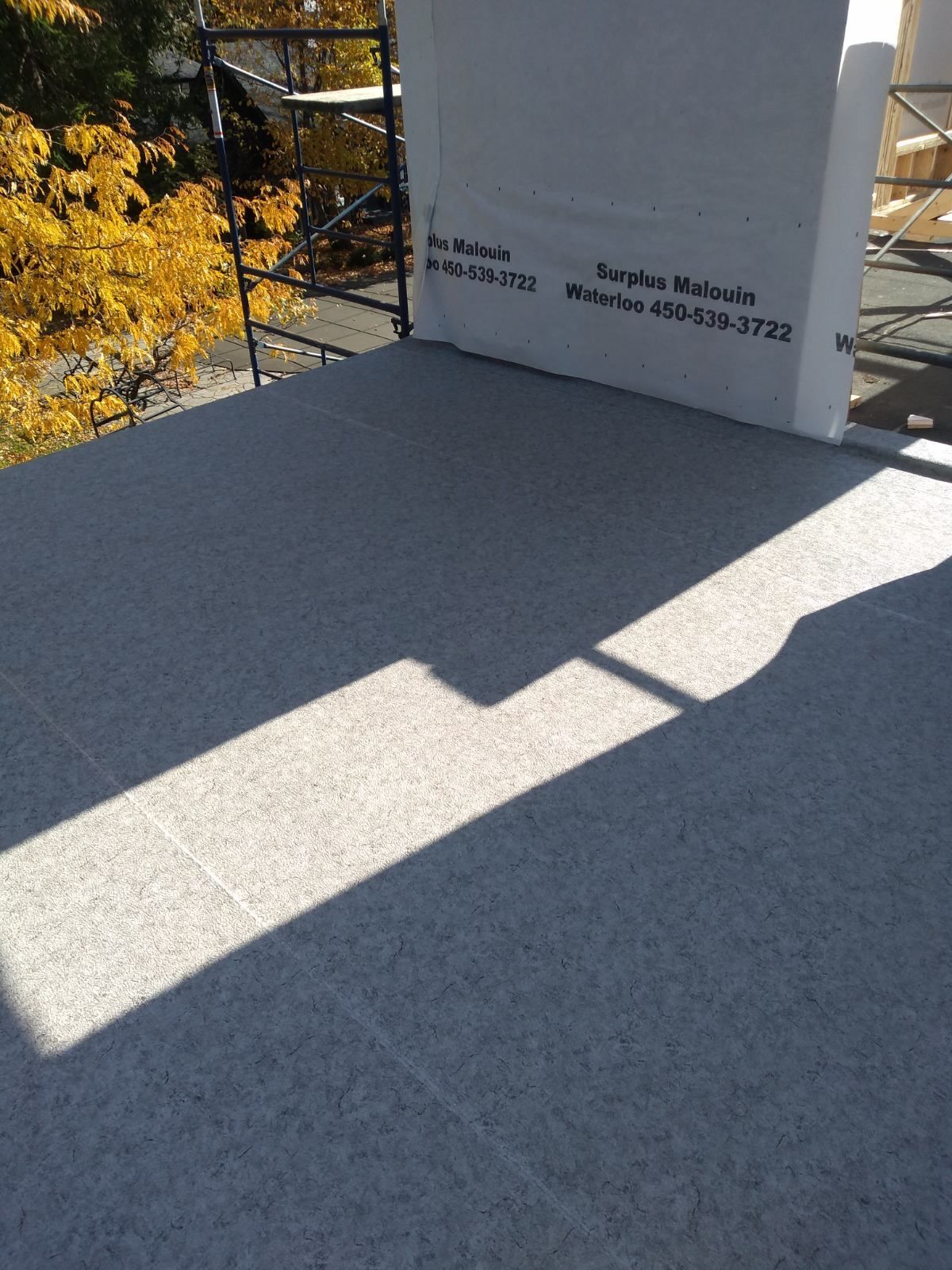 L'ombre d'une personne est projetée sur un sol recouvert de membrane de PVC