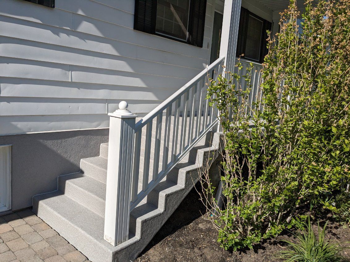 Un ensemble d'escaliers couverts de membrane de PVC menant à une maison avec une rampe blanche.