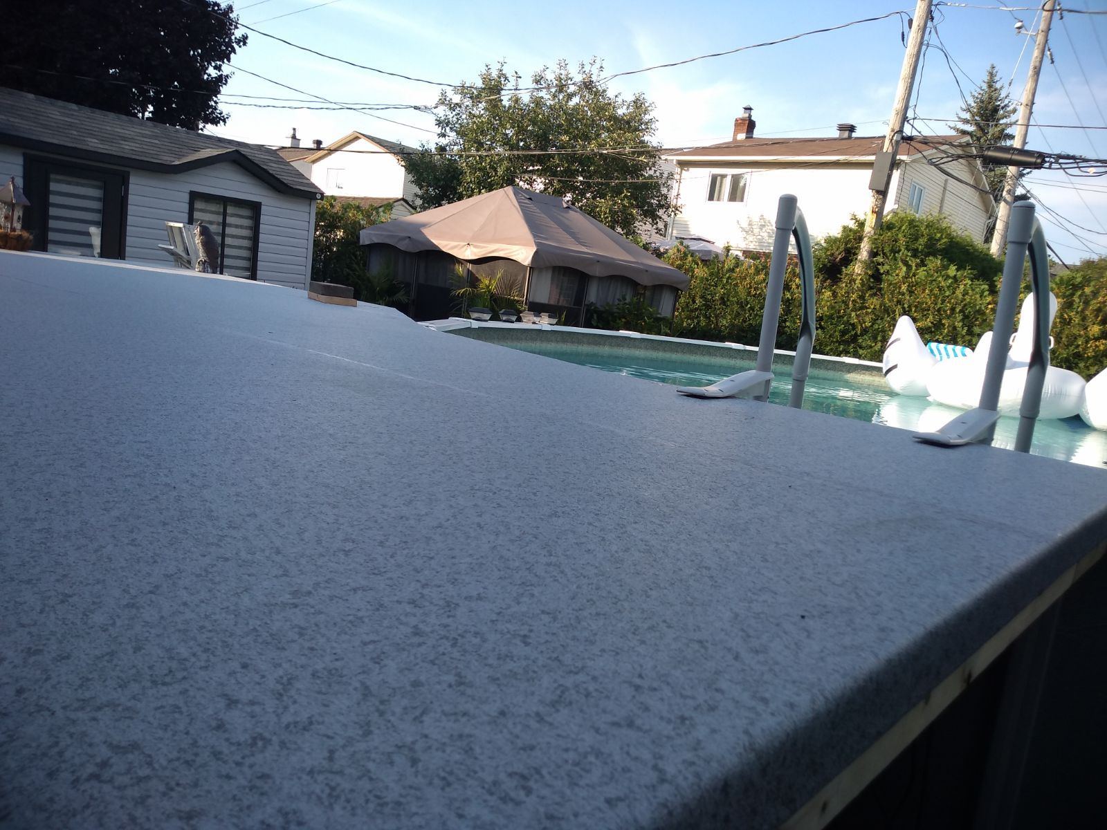 Une piscine avec un patio et une maison en arrière-plan