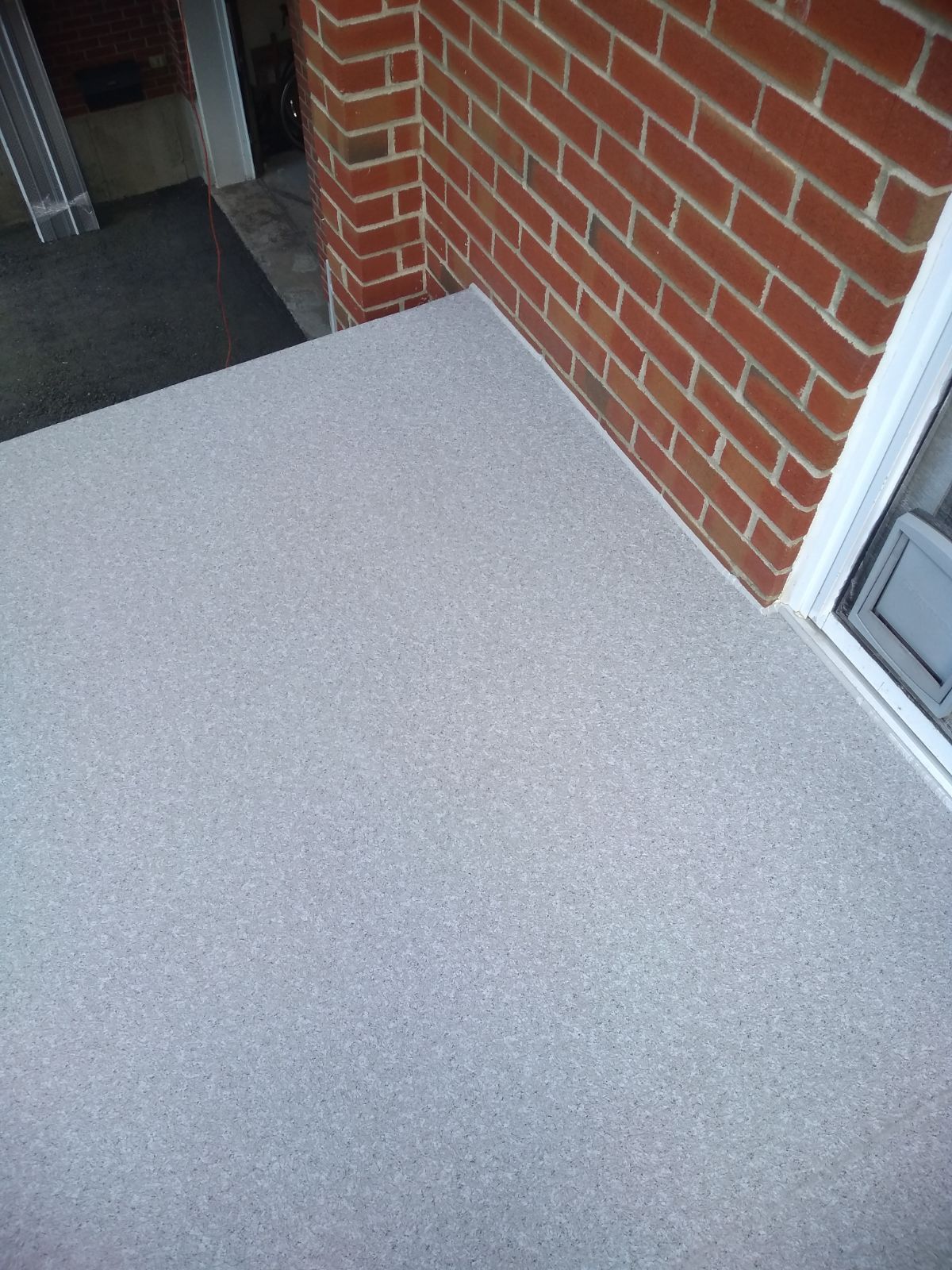 Un mur de briques avec un sol gris en membrane de PVC devant