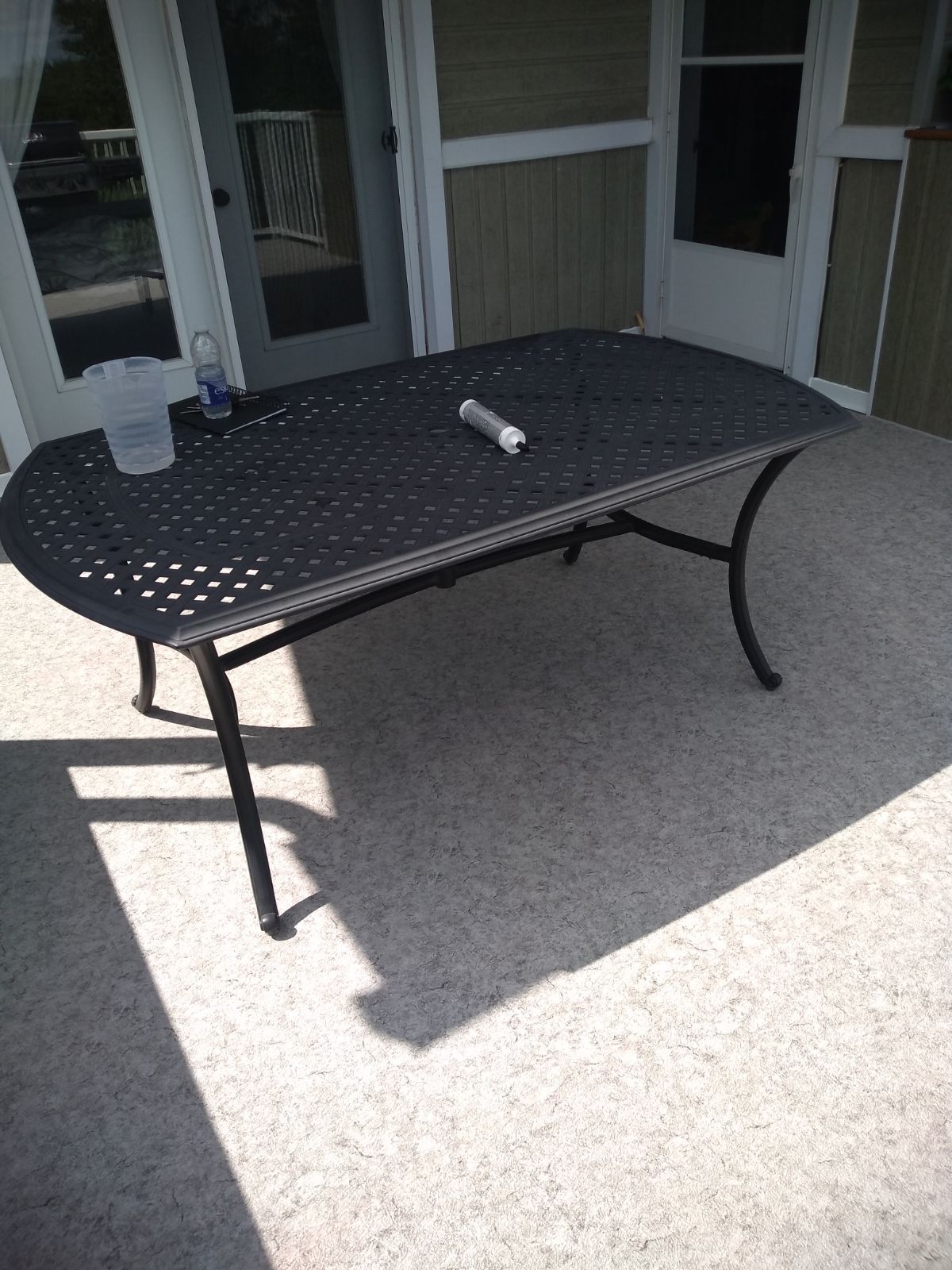 Une table noire est posée sur un patio à côté d'une fenêtre.