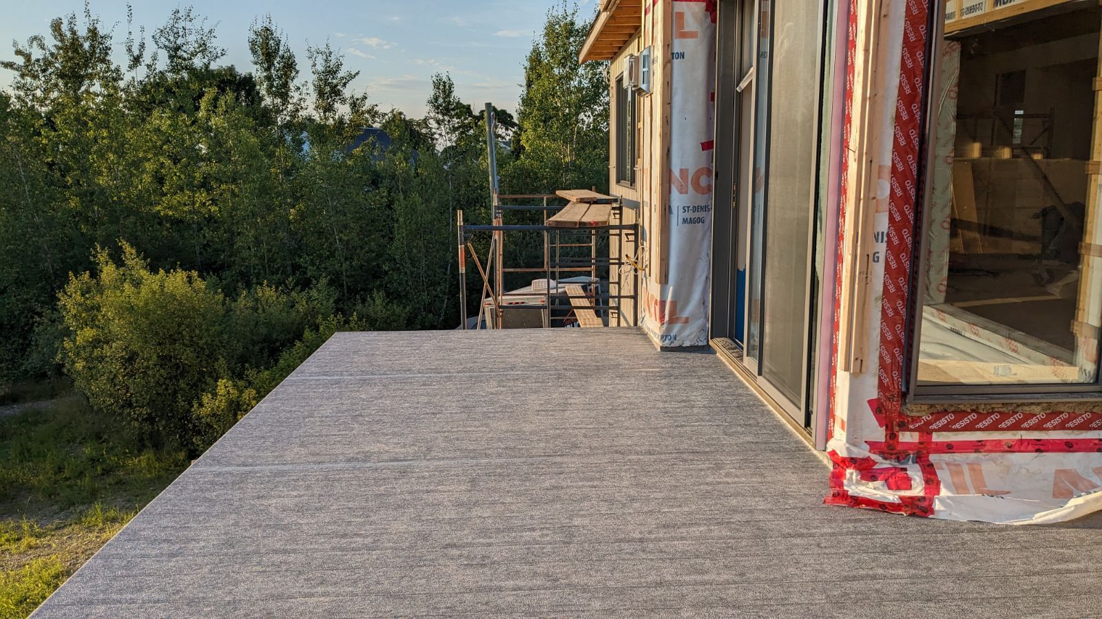 Une grande terrasse en PVC est en cours de construction sur le côté d'une maison.