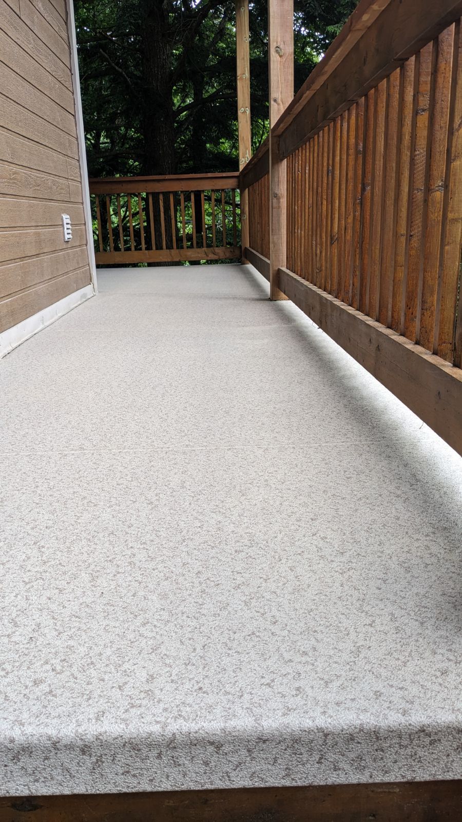 Une terrasse en membrane de PVC avec une rampe en bois.