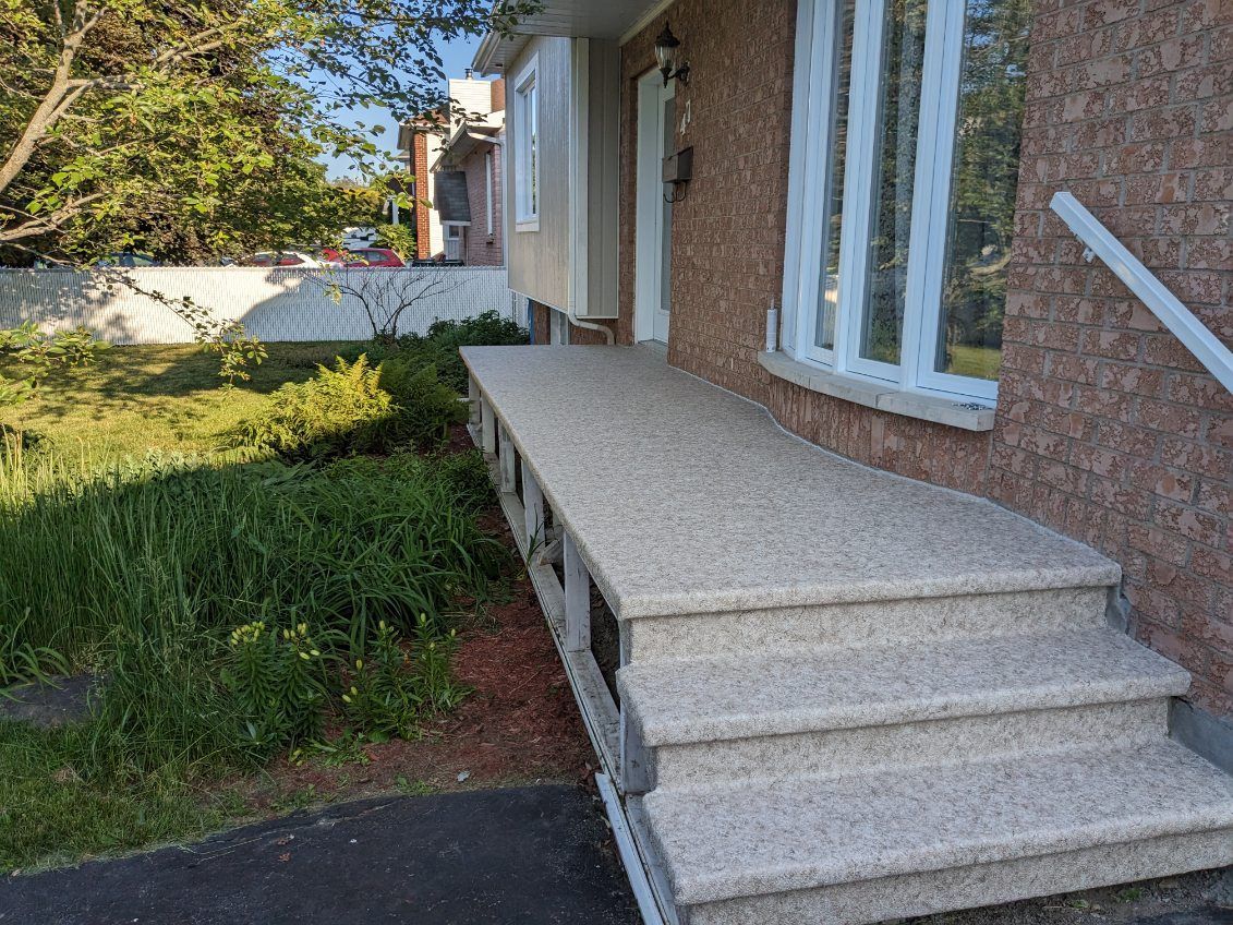 Une maison en briques avec un porche et des escaliers devant.