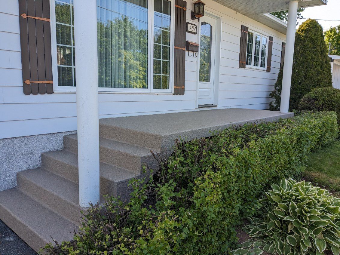 Une maison blanche avec un porche en PVC et des escaliers devant.