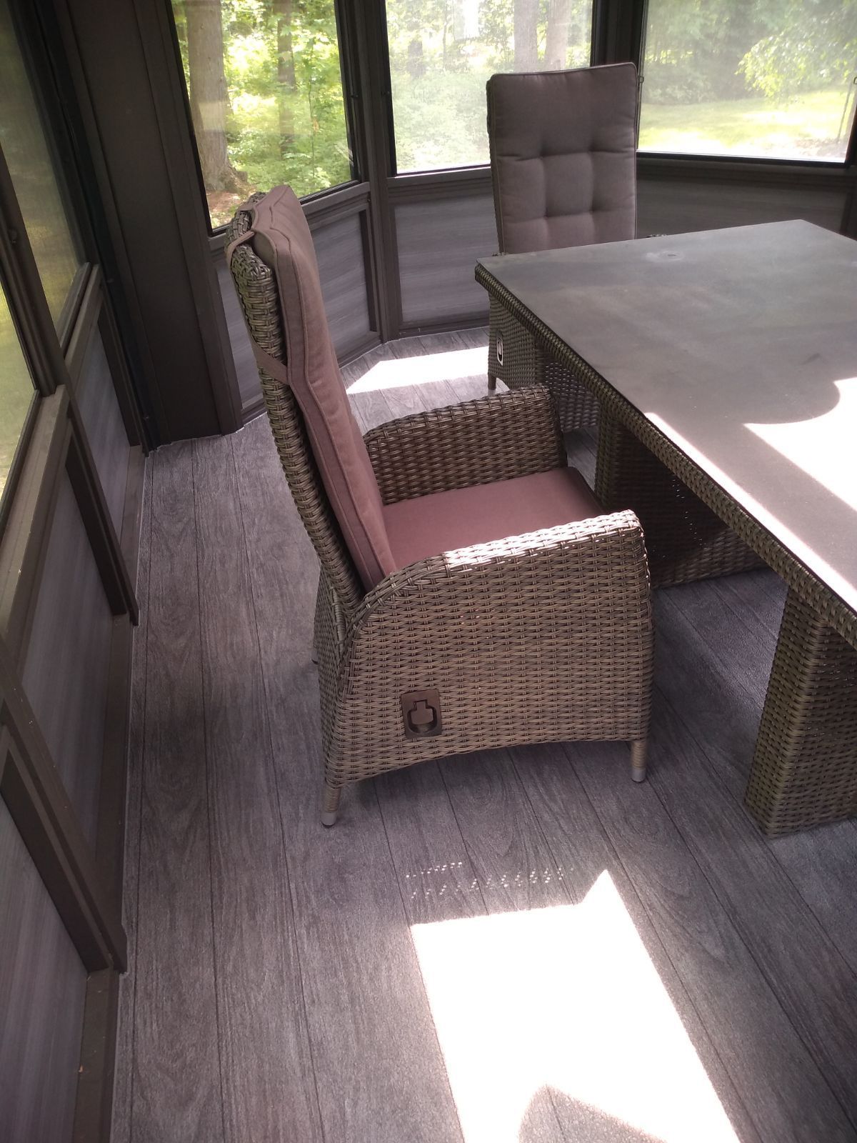 Une chaise en osier est assise à côté d'une table dans une pièce avec un plancher en PVC