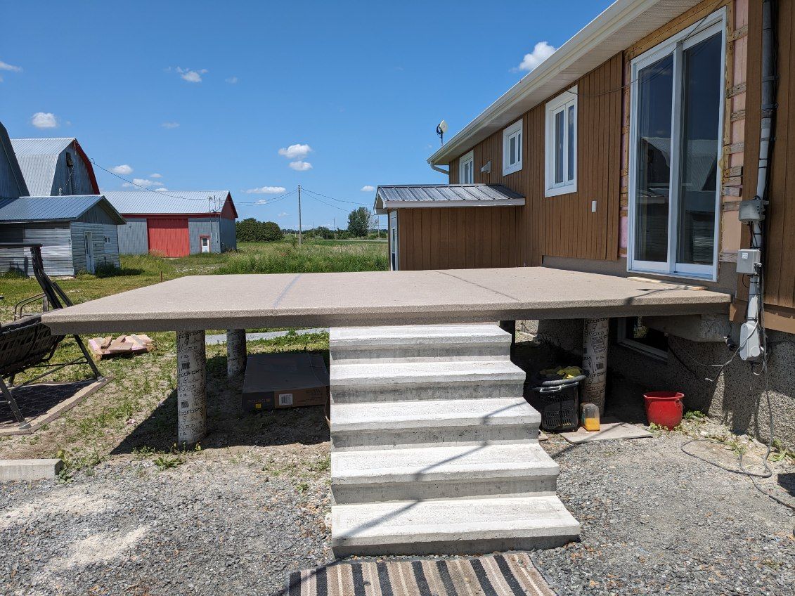 Une maison avec une terrasse en membrane de PVC et des escaliers devant.