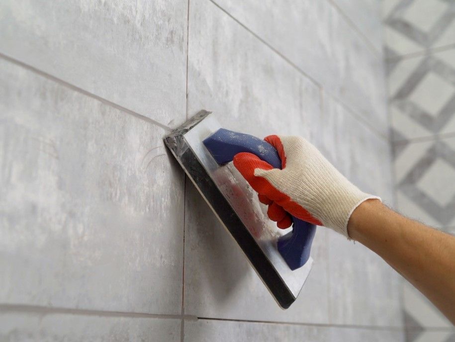 a tiler in derby smoothing the grout between bathroom tiles