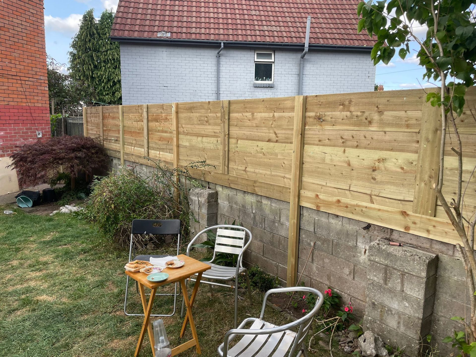 Wooden fencing installed on top of a brick wall in a garden in Cardiff
