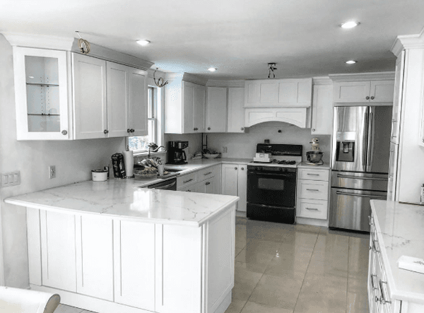 White kitchen with marble countertops, stainless steel appliances, and black stove.