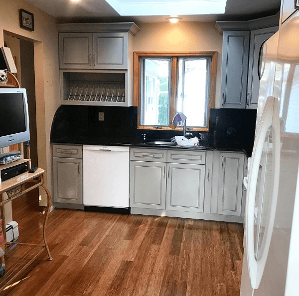 Kitchen with grey cabinets, white appliances, black countertops, and wood floor.