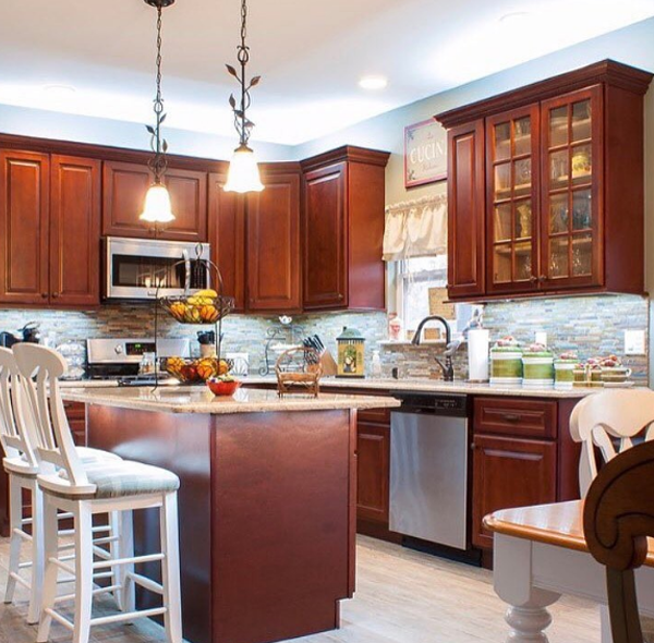 Kitchen with reddish-brown cabinets, stainless steel appliances, and a granite countertop island; two pendant lights.