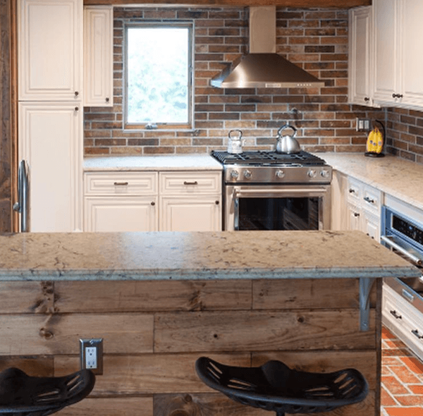 Kitchen with brick backsplash, white cabinets, stainless steel appliances, and a wood-paneled island with seating.