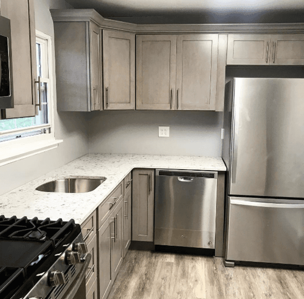 L-shaped kitchen with gray cabinets, stainless steel appliances, and light countertops.