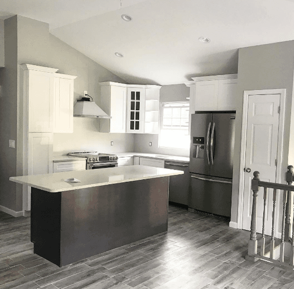 Modern kitchen with white cabinets, stainless steel appliances, and dark island. Gray walls and flooring.