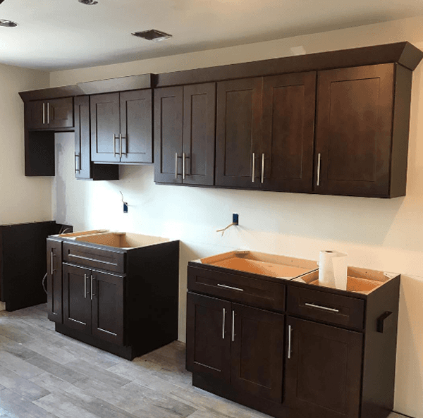 Dark brown kitchen cabinets installed on a white wall. Unfinished kitchen with lower cabinets and upper cabinets.