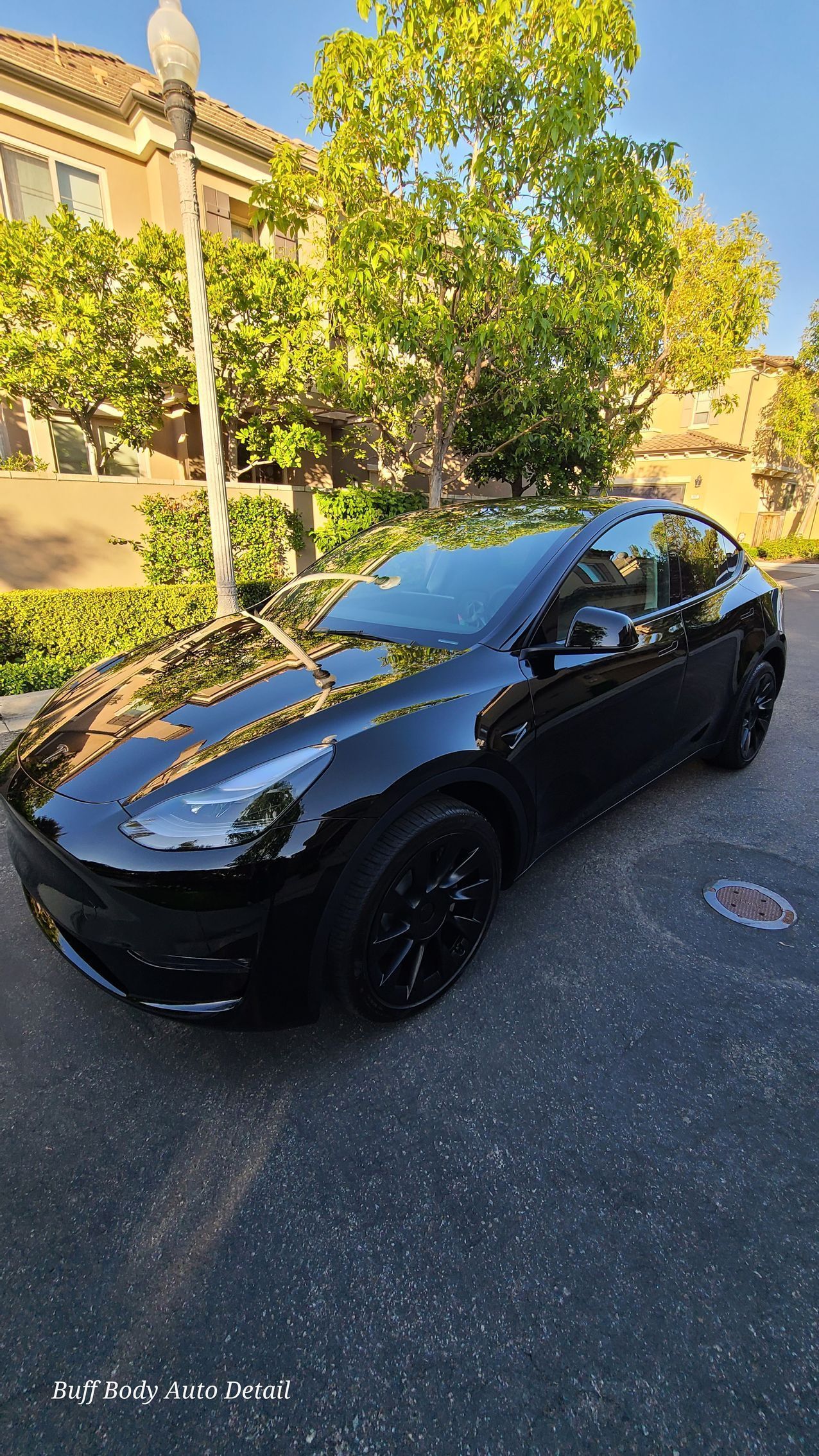 A black tesla model y is parked on the side of the road.