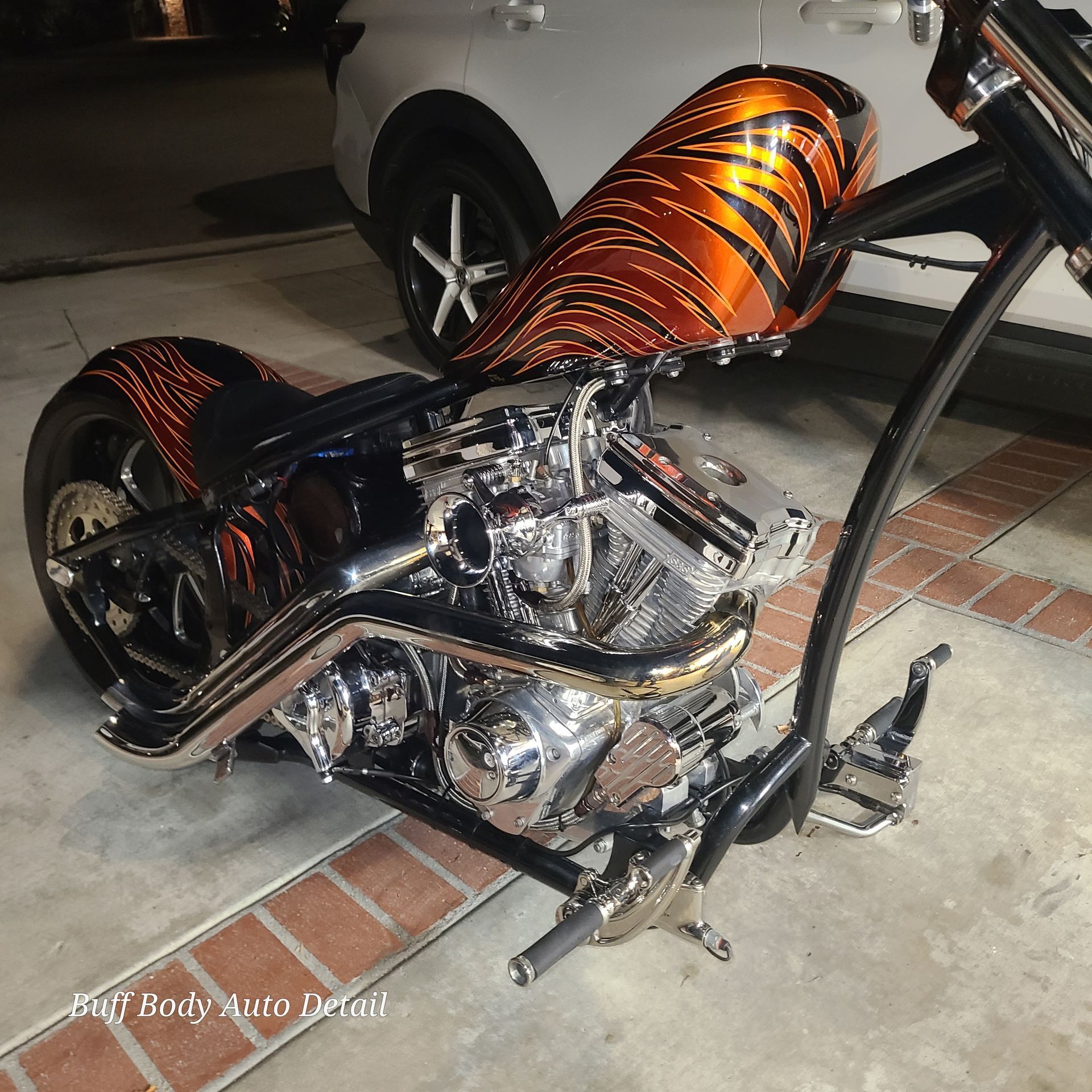 A black and orange motorcycle is parked in a driveway