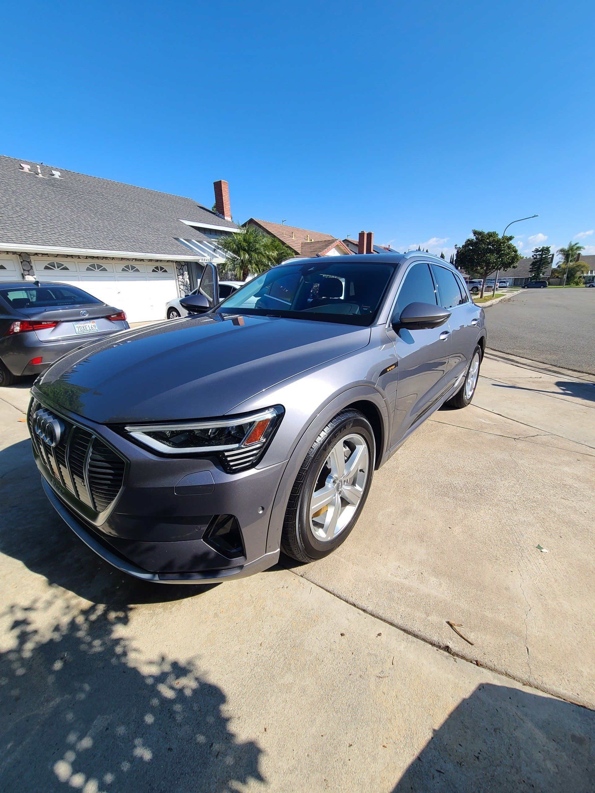 A gray car is parked in a driveway in front of a house