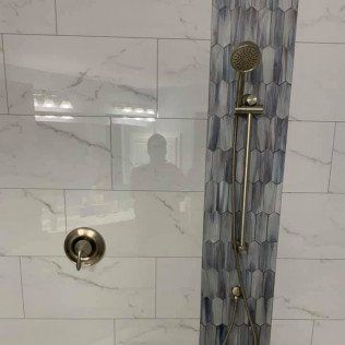 A shower with a sliding glass door and a shower head.