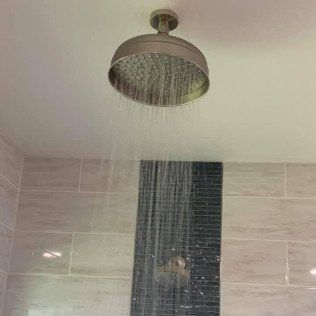 A shower head is hanging from the ceiling in a bathroom.