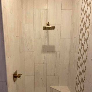 A shower with a shower head and a corner shelf.