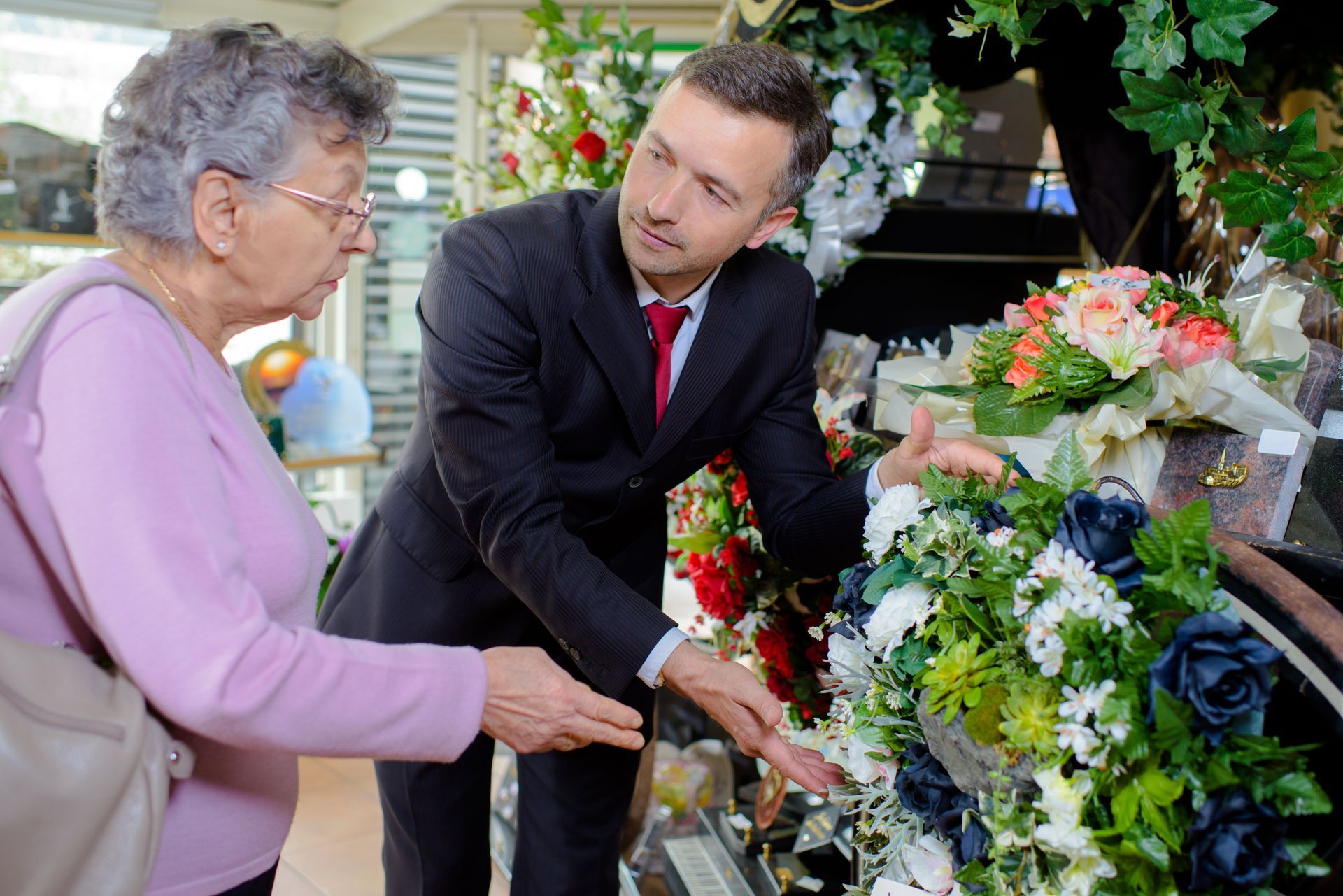 a man and a woman are looking at flowers in a store .