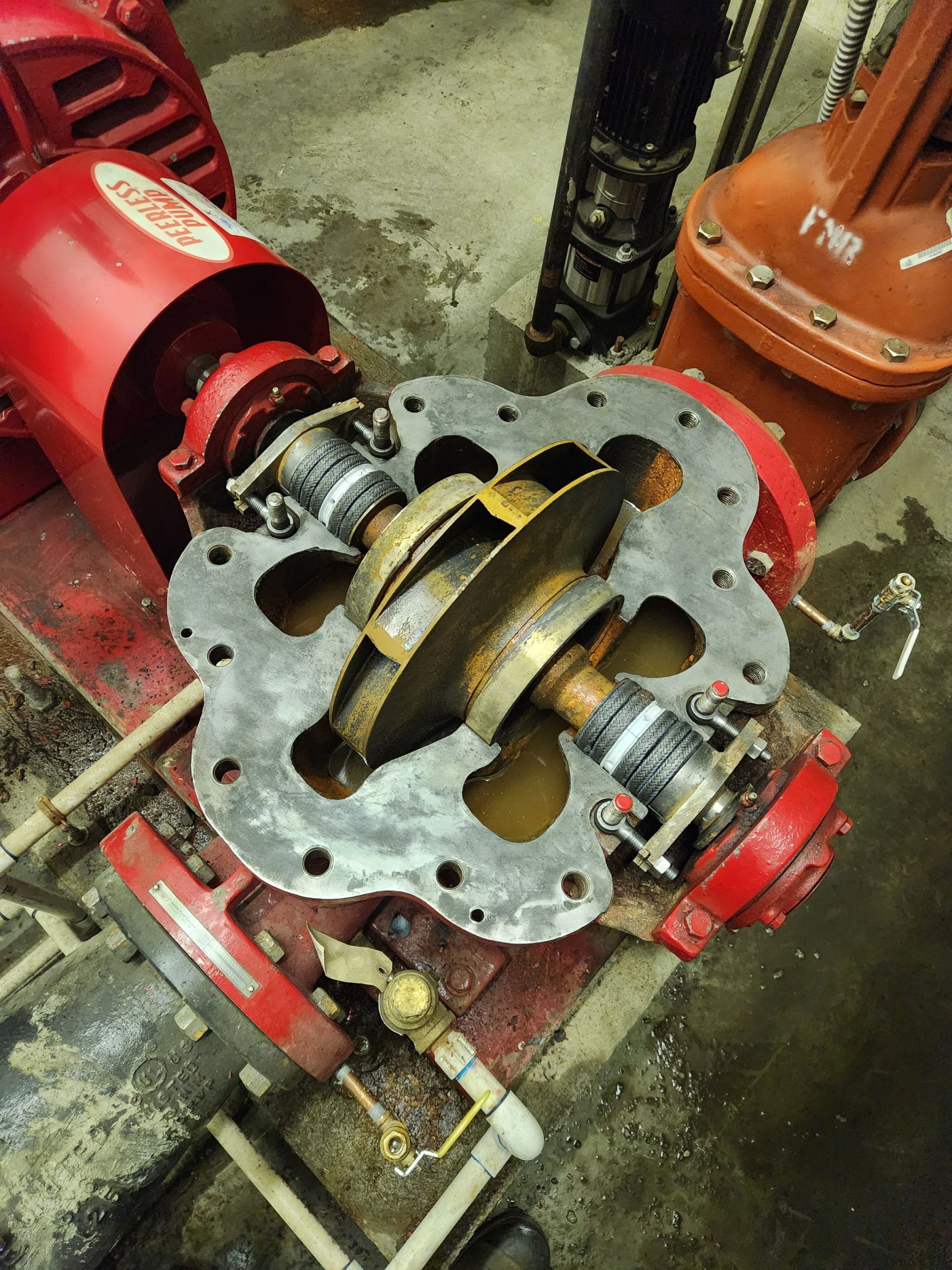 A red pump is sitting on top of a concrete floor.
