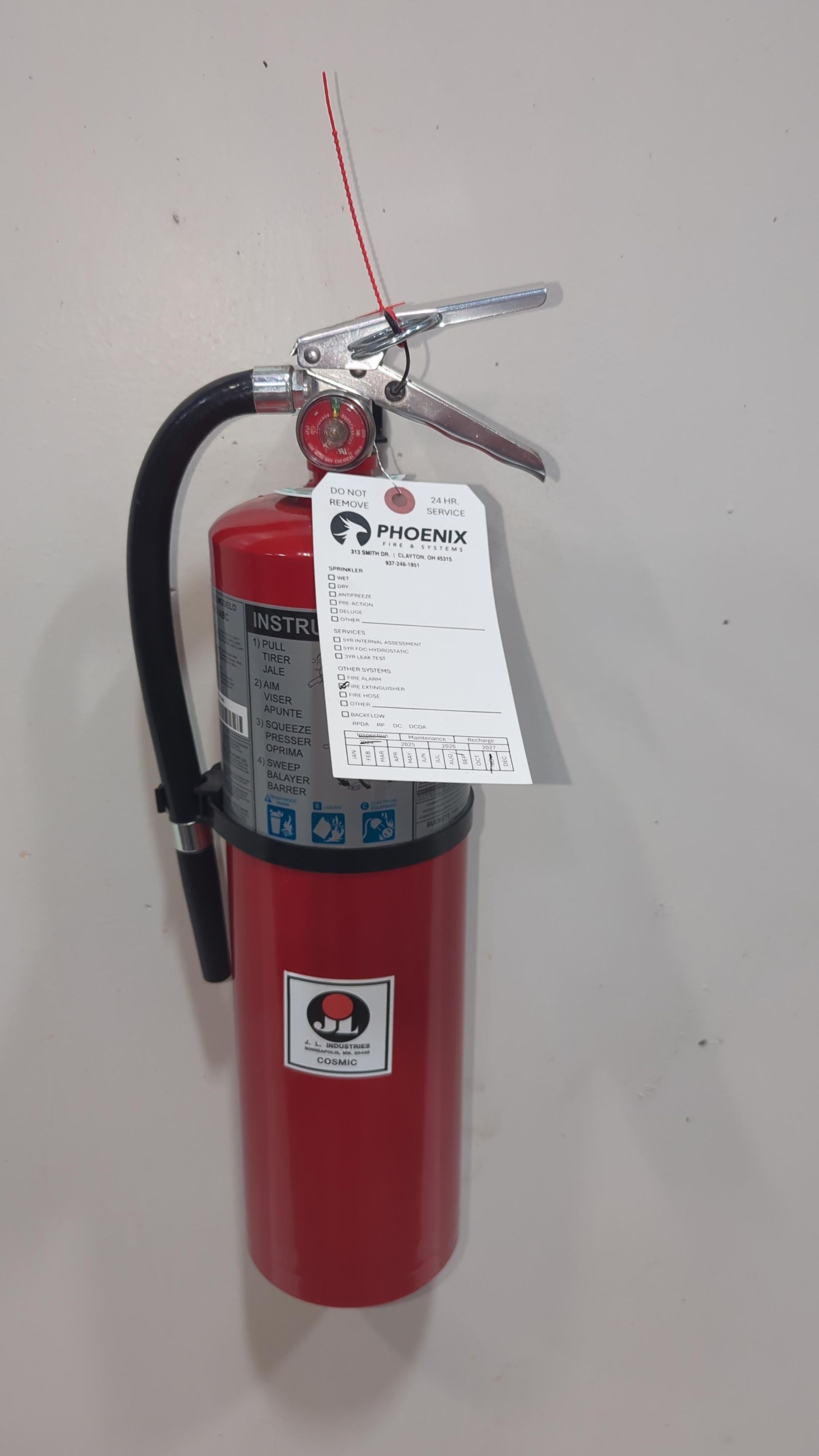 A red fire extinguisher with a tag attached to it is hanging on a wall.