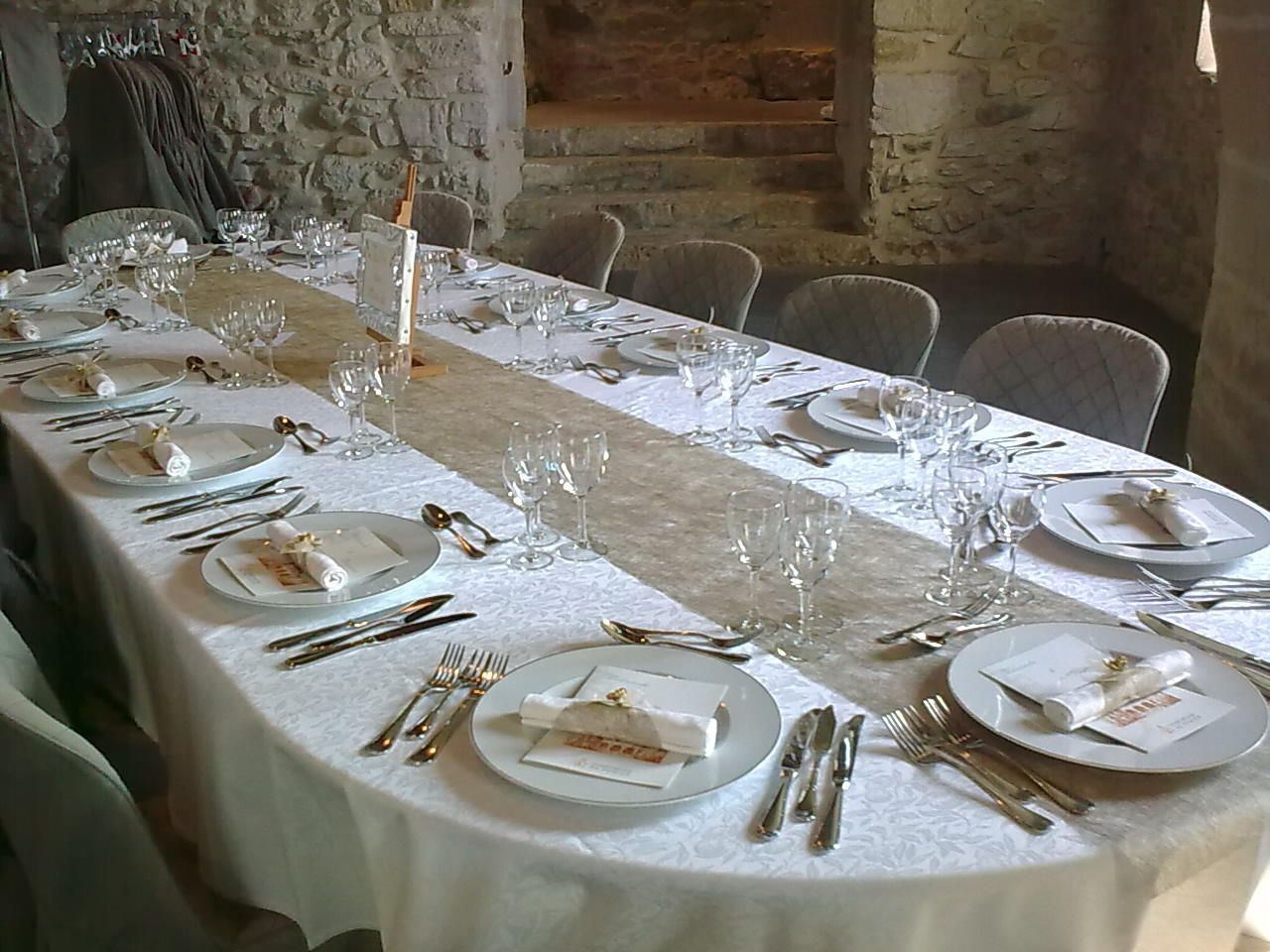 Élégante table à manger dressée avec assiettes, verres et serviettes blancs dans une salle en pierre rustique