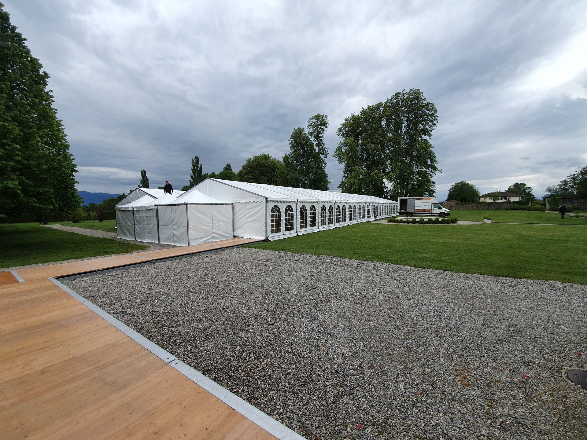 Grande tente blanche vide avec un plancher en bois et un petit tabouret noir au centre