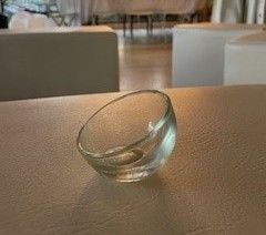Petit bol en verre transparent posé sur une table dans un coin salon intérieur à l'éclairage tamisé.