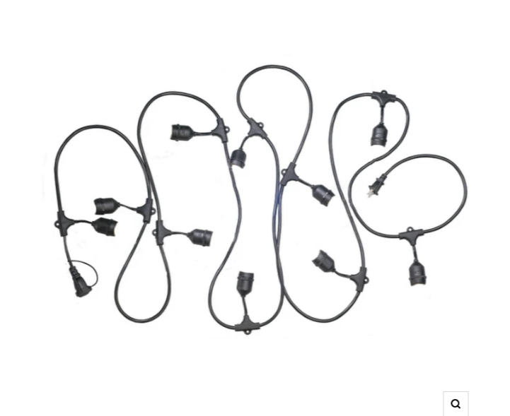 Des guirlandes lumineuses aux tons chauds illuminent un mur extérieur sombre au crépuscule.