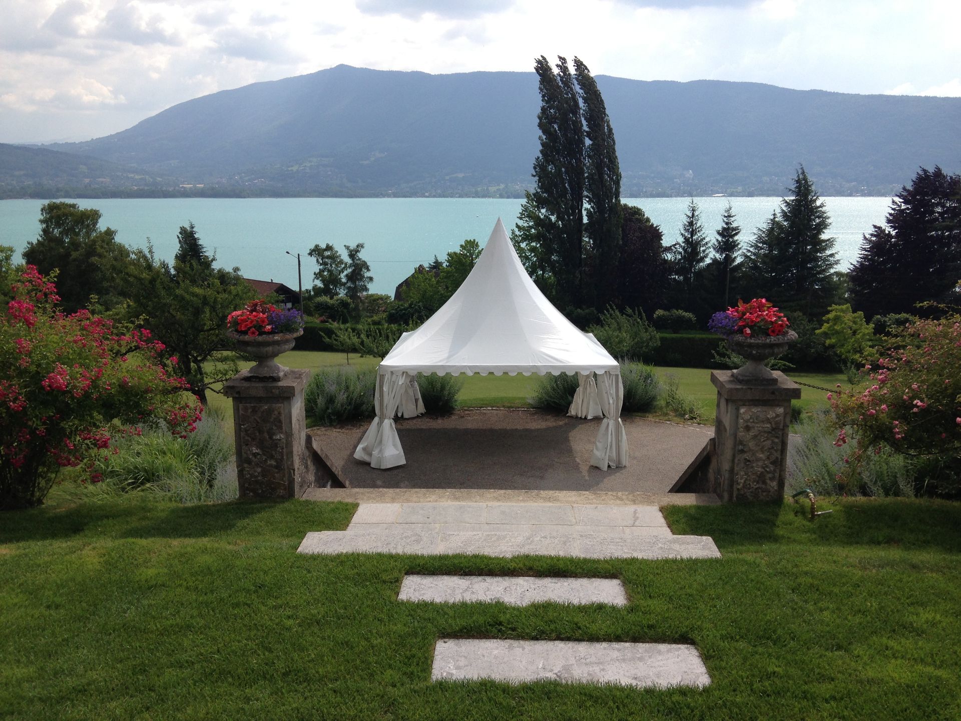 Des tentes blanches près d'une fontaine jaillissant d'un étang dans un parc verdoyant
