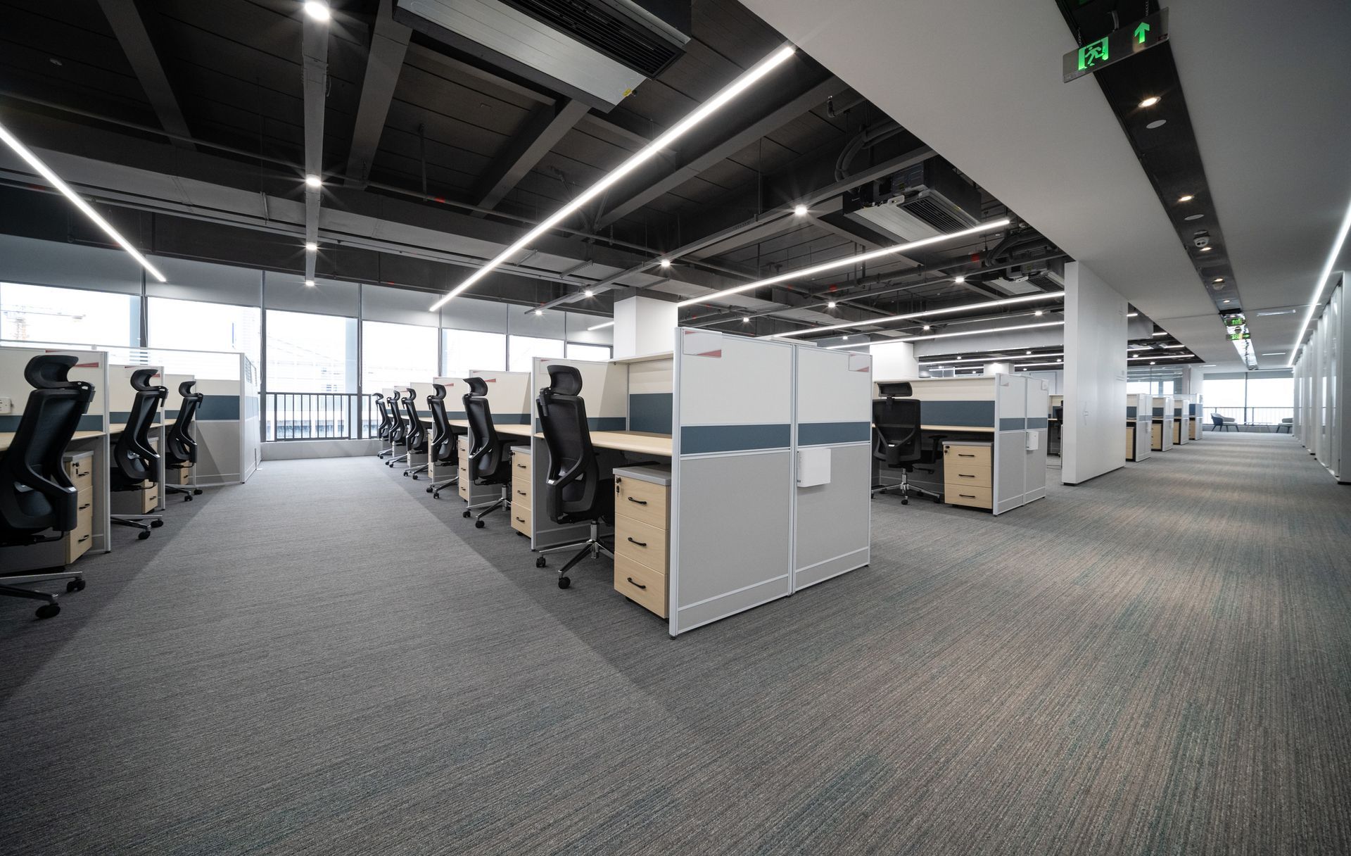 A large empty office with a lot of cubicles and chairs.
