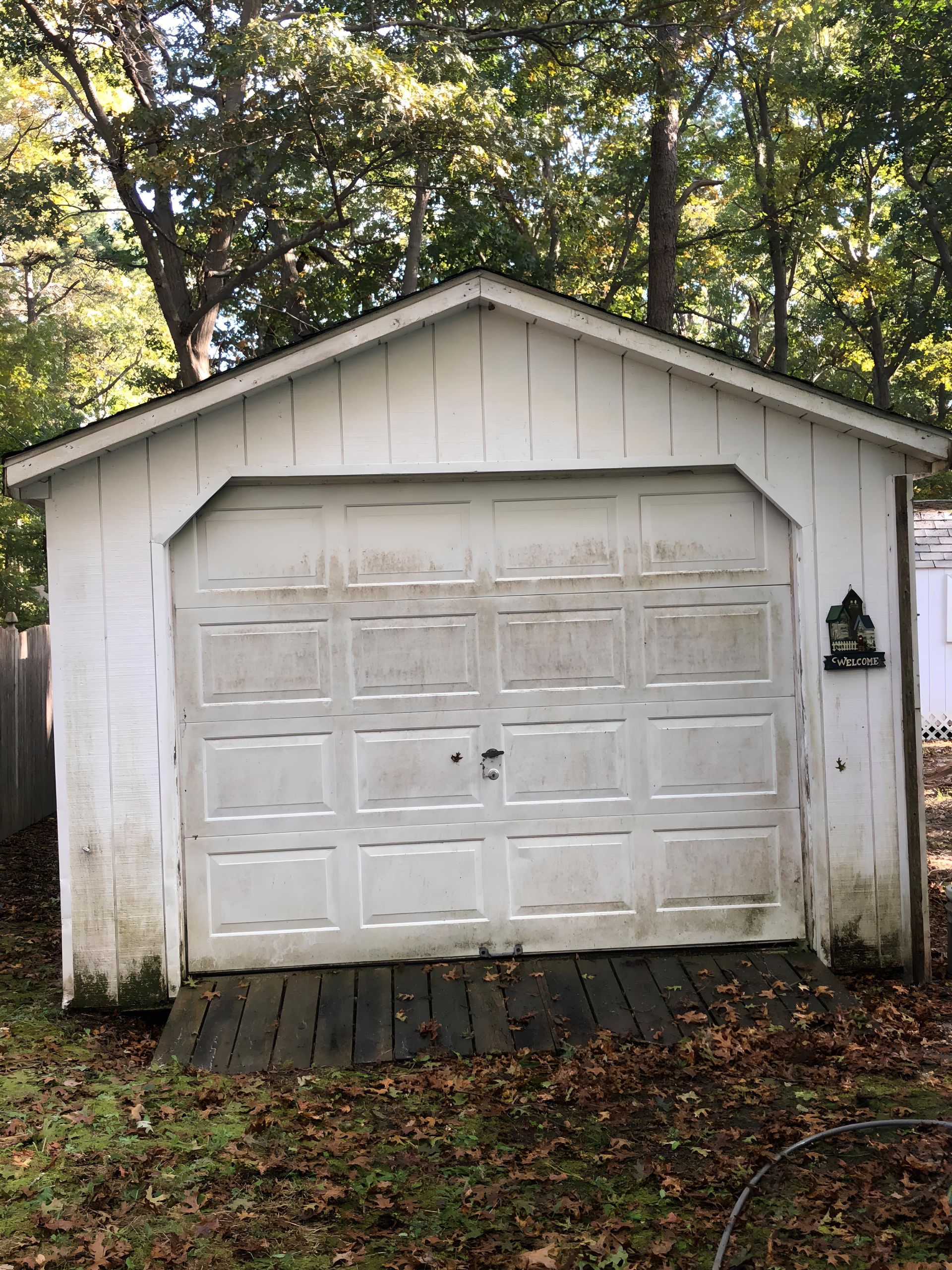 A white garage with a wooden ramp leading to it