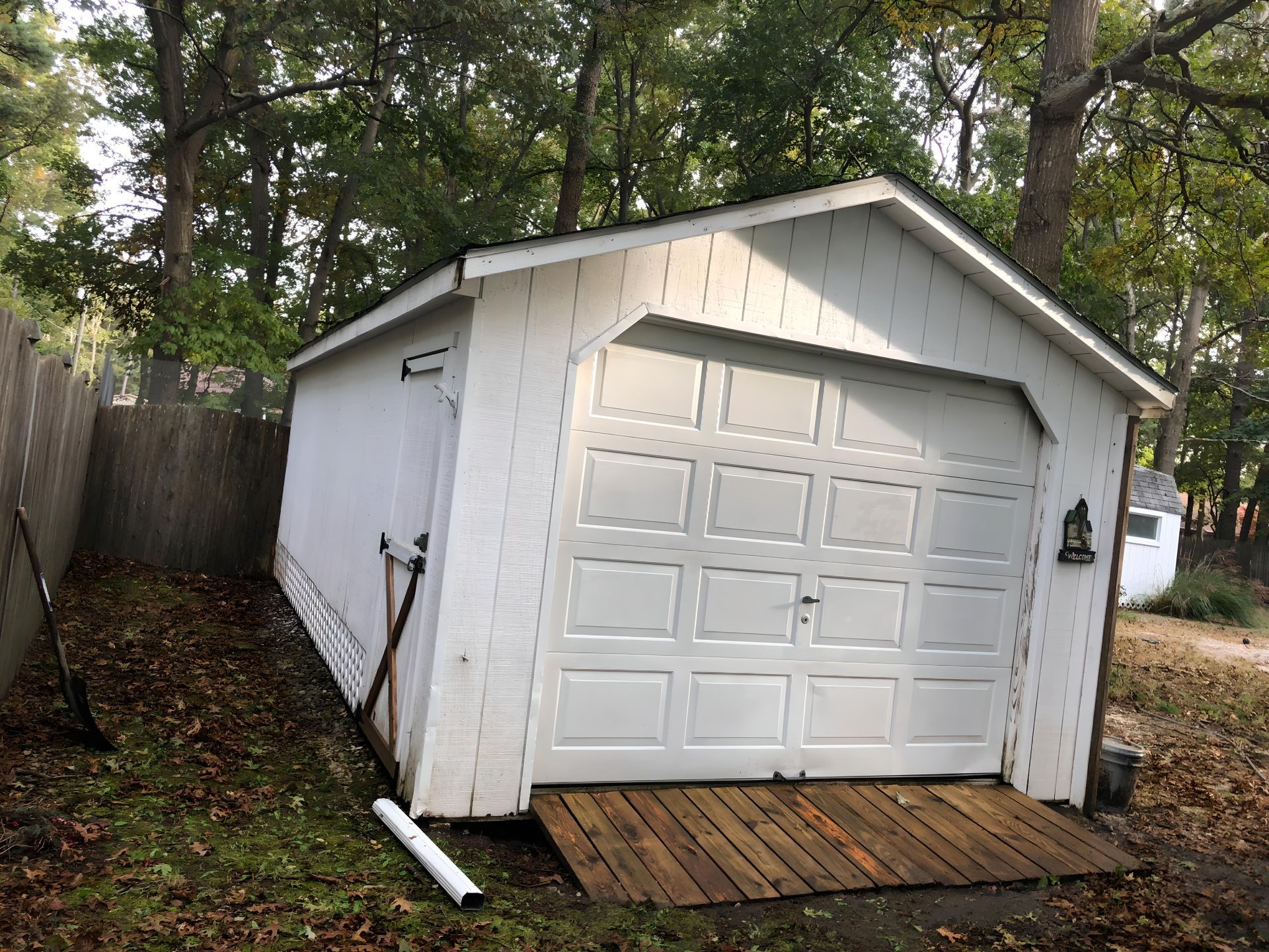 A white garage with a wooden ramp leading to it