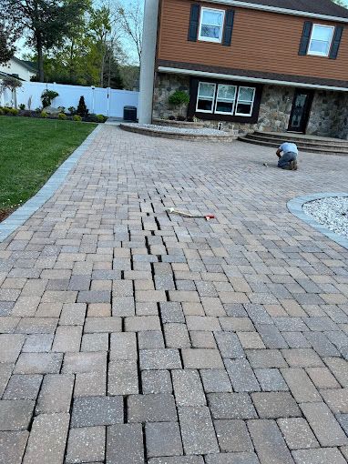 melo powerwashing & painting employee on their knees repairing cracked brick driveway in somers point, nj