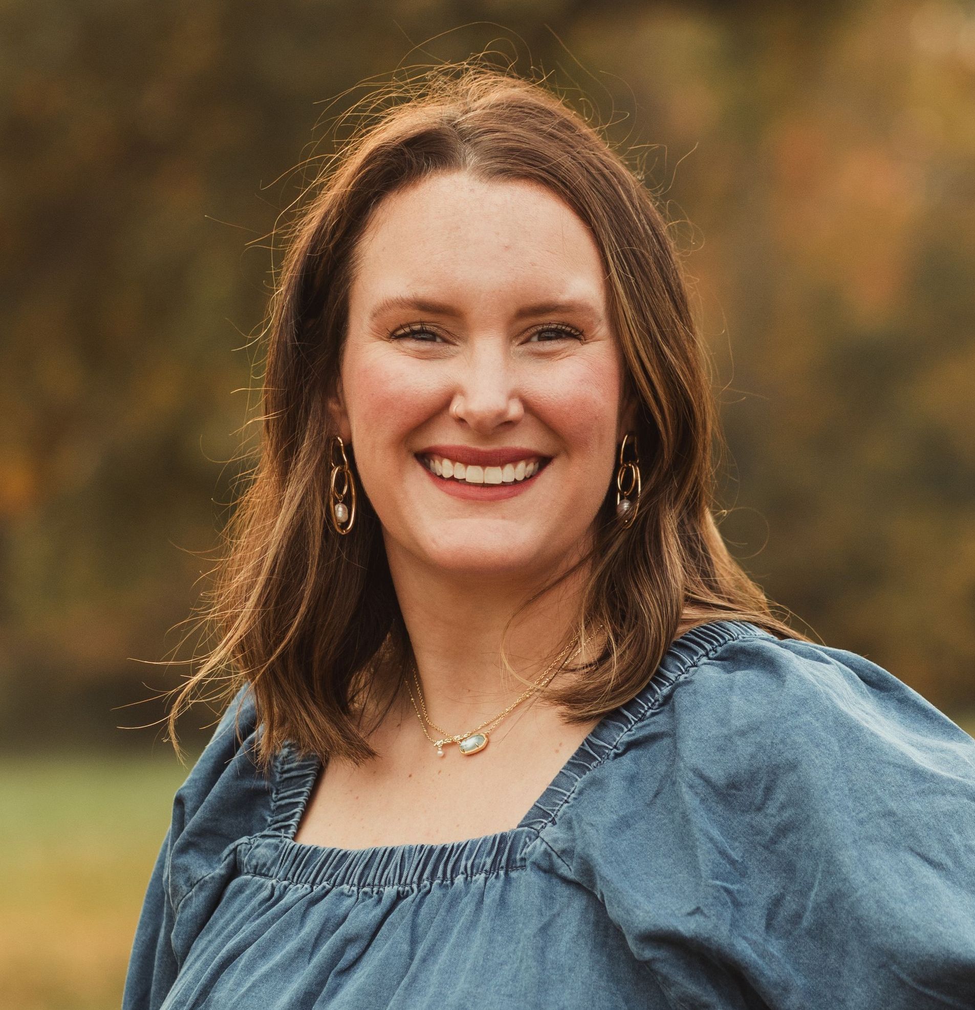 A woman in a blue dress is smiling for the camera.